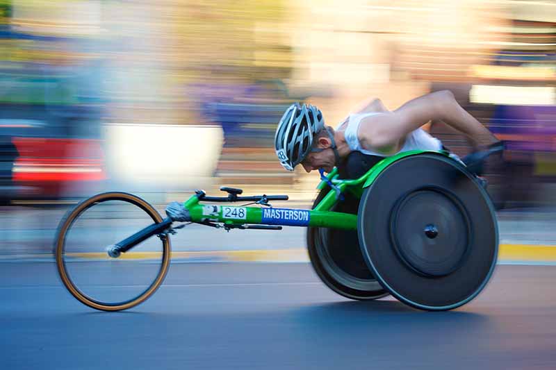 Picture of speed racing para athlete on a green wheelchair bike