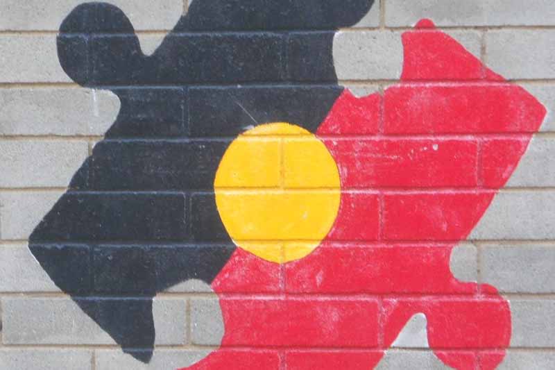 Picture of an aboriginal flag painted on a wall in the shape of a jigsaw puzzle peice