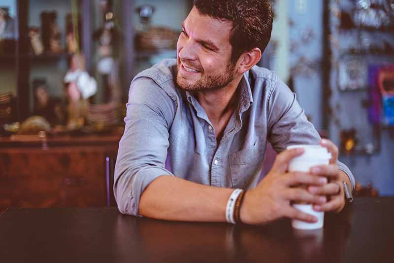 Picture of a guy sitting at a cafe smiling