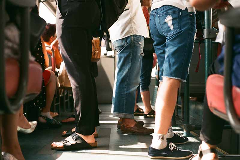 Picture of peoples legs standing on a pubic bus