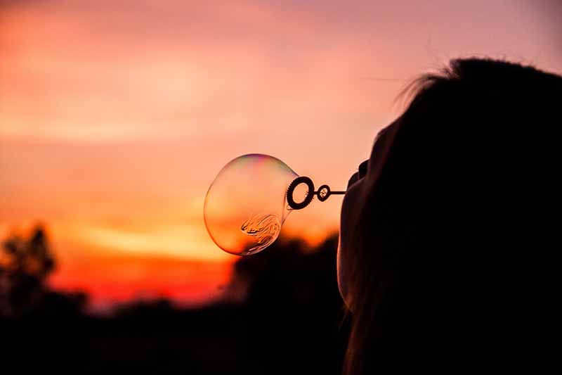 Picture of a girl blowing bubbles in the light of a sunset