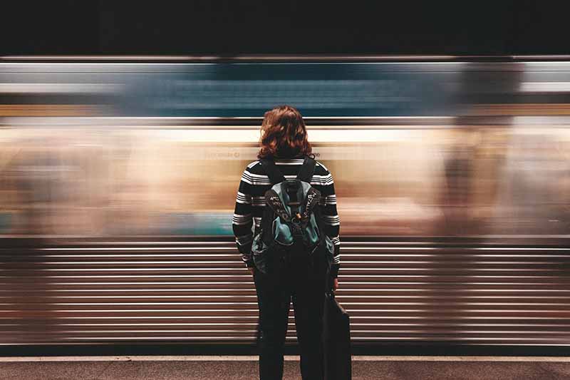 Picture of a lady on a train platform with the train going past very fast